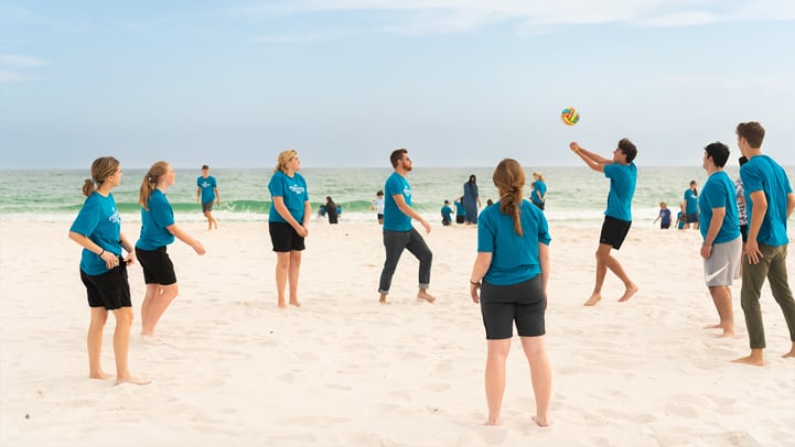 Students playing volleyball on the beach