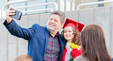 Graduate taking selfie with dad