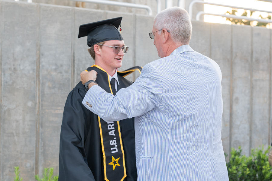 Father helping graduate with regalia