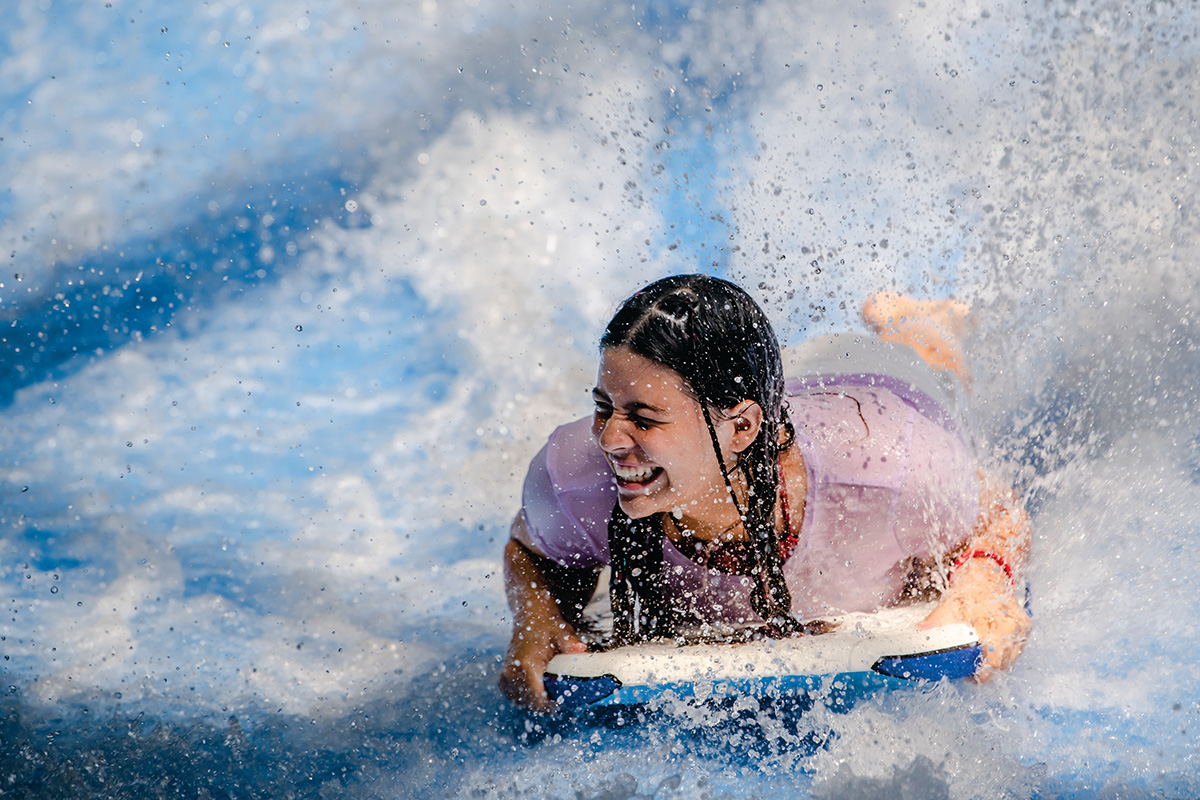 Teen Extreme camper riding flowrider on boogie board