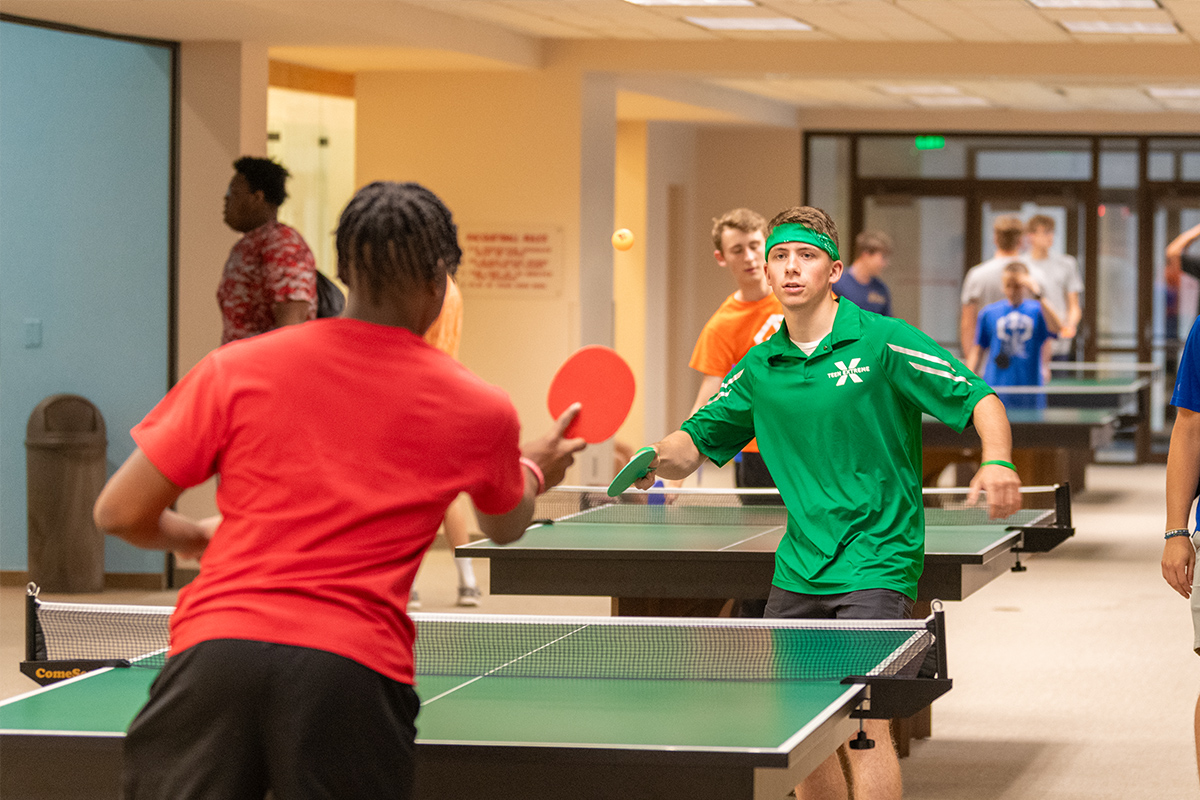 Teen Extreme camper and green camp staff playing ping-pong